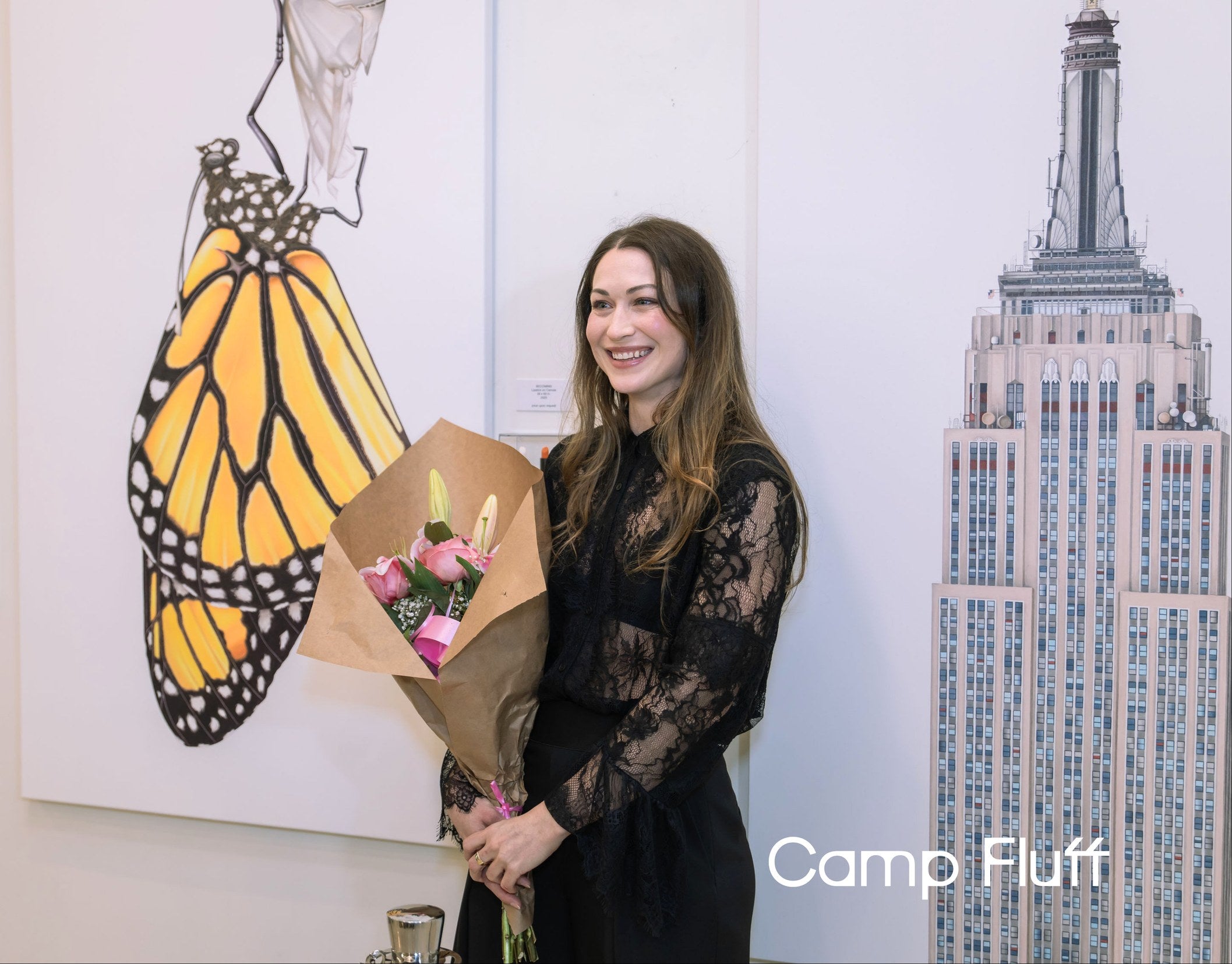 Katherine Mason holding a bouquet in front of her painting Becoming in New York