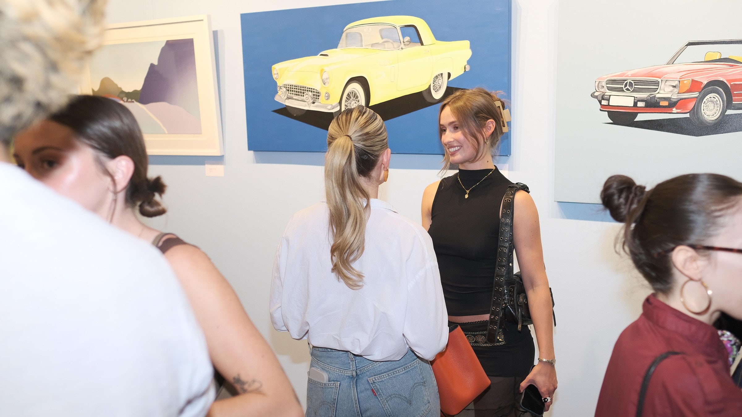 Guests talking in front of the car paintings in Los Angeles