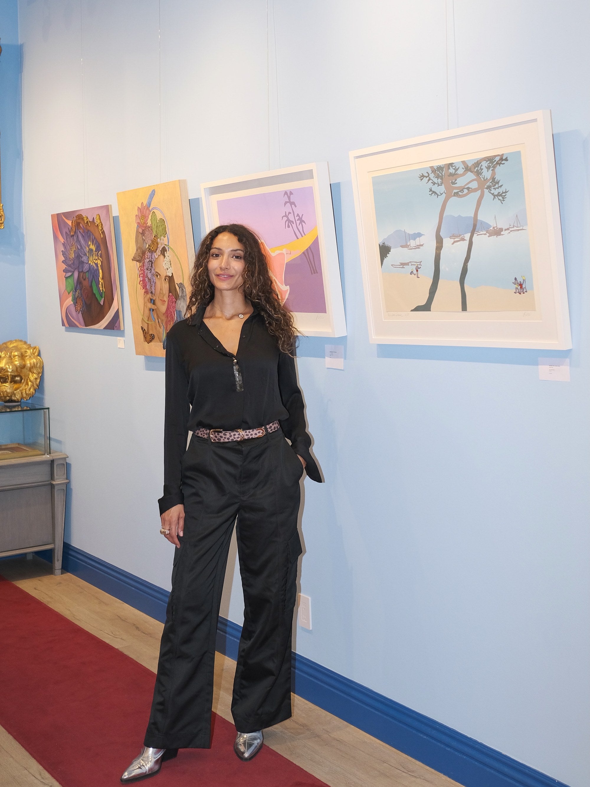 An artist standing in front of her paintings in Los Angeles